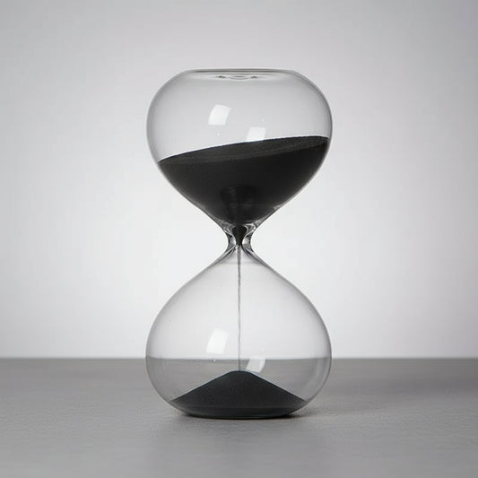 Hourglass with sand running through on a wooden surface