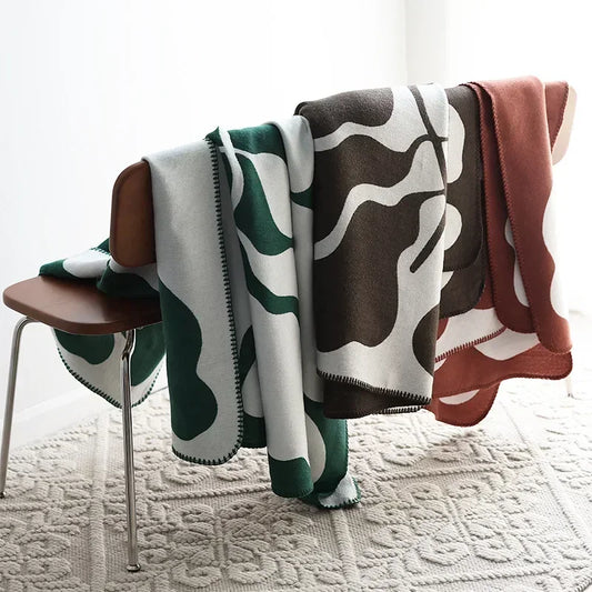 Three patterned blankets draped over a chair on a textured floor.