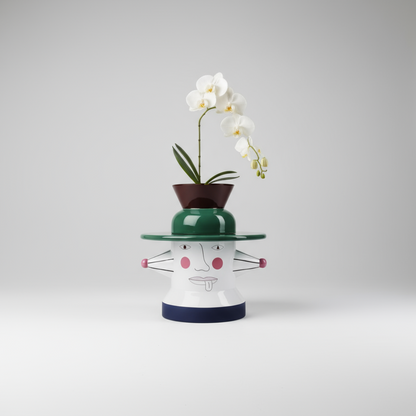 Decorative vase with a face design and a white orchid on a gray background