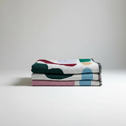 Colorful abstract-patterned blanket draped over a rack against a white wall.