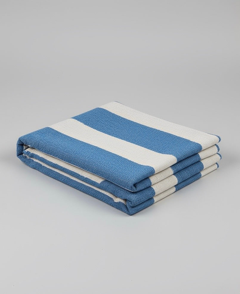 Folded blue and white throw on a gray background