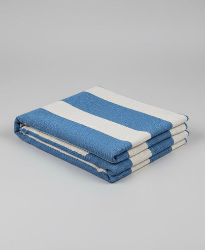 Folded blue and white throw on a gray background