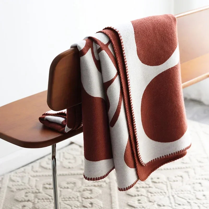 Brown and white patterned blanket draped over a wooden chair on a light-colored floor.
