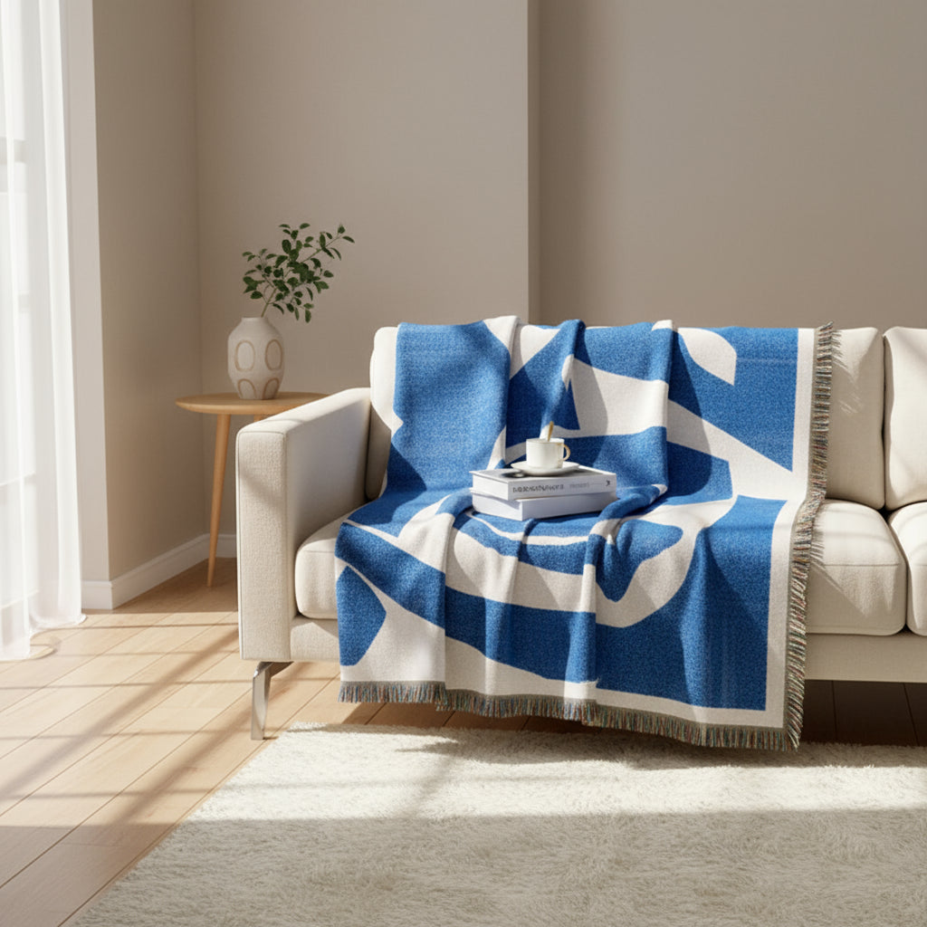 Blue and white patterned throw blanket draped over a beige sofa in a living room.