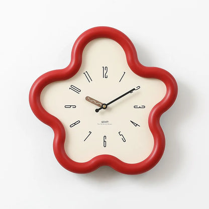 Decorative wall clock with a red frame on a gray surface against a white wall.