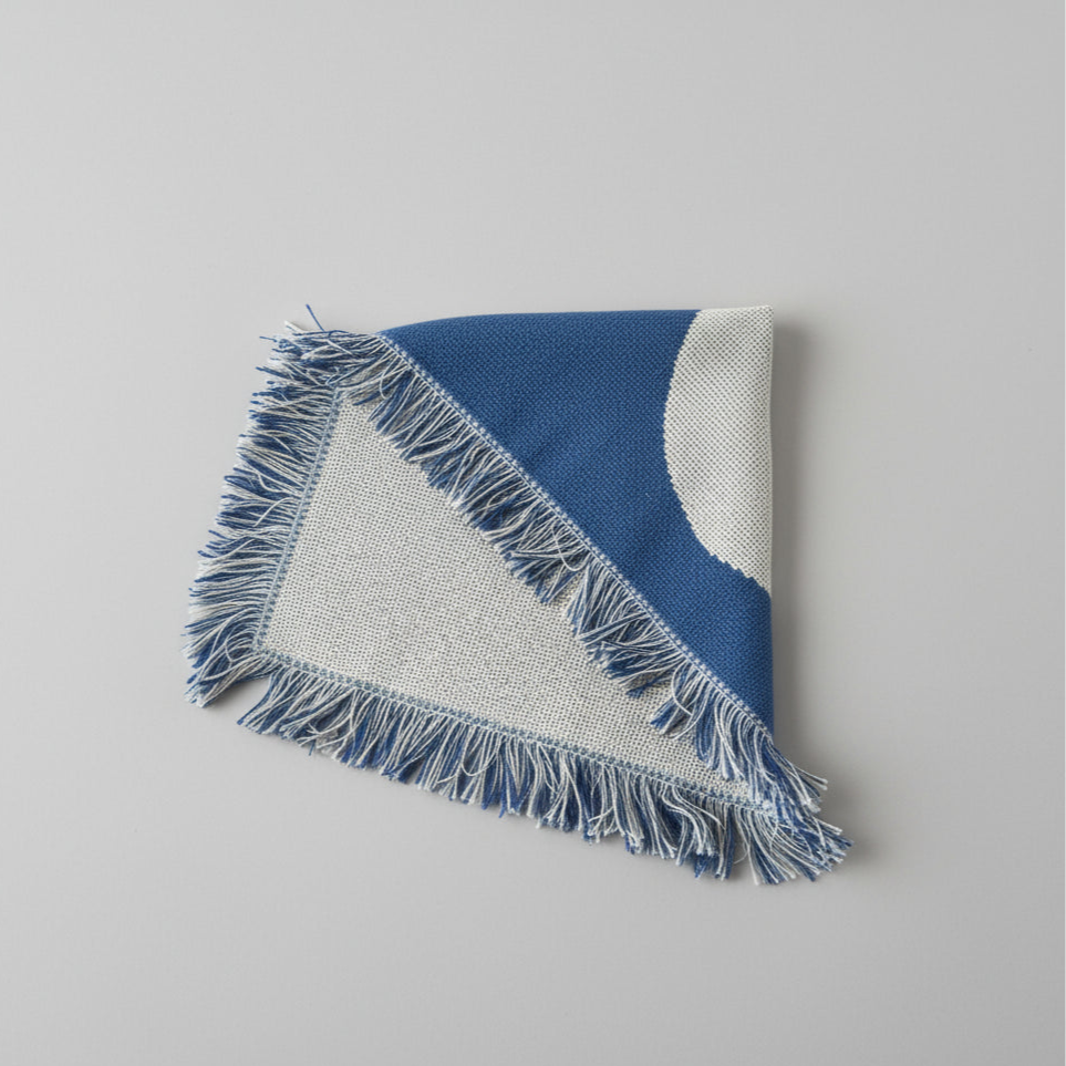 Blue and white throw with frayed edges on a gray background