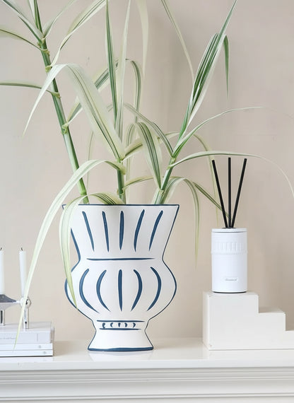 Decorative vase with plant and diffuser on a shelf against a neutral wall
