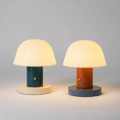 Two colorful table lamps on a surface with books underneath.