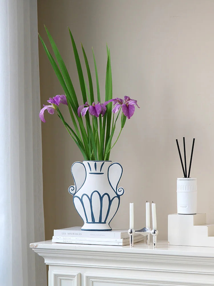 Decorative vase with purple flowers on a white surface against a beige wall