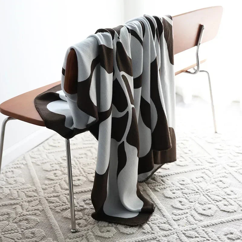 Patterned blanket draped over a chair on a textured floor