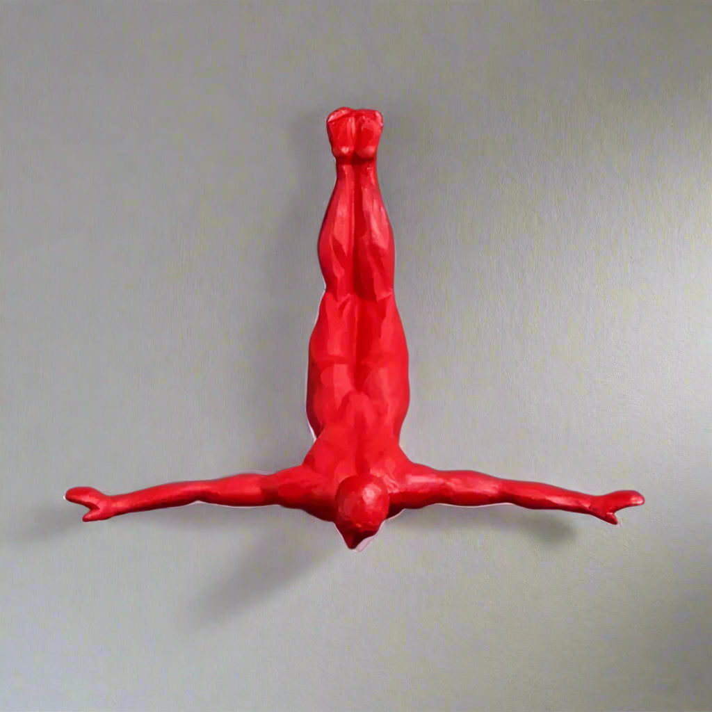 Red figure of a person in a handstand pose  on a gray wall