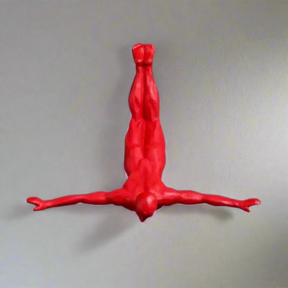 Red figure of a person in a handstand pose  on a gray wall