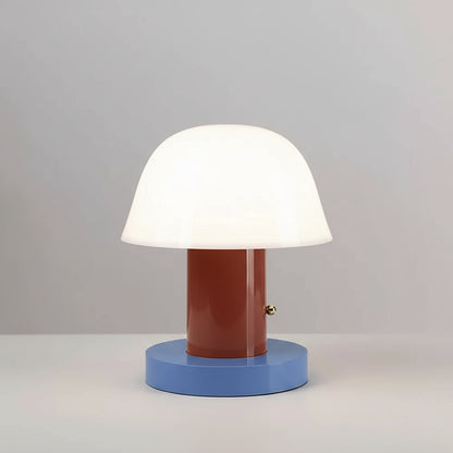 Table lamp with a white shade, brown cylindrical middle section, and blue base on top of books.