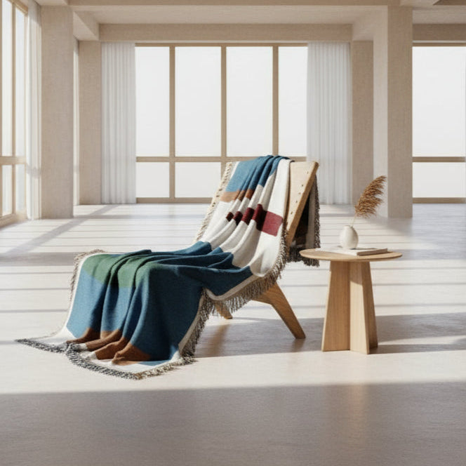 Chair with a colorful blanket draped over it in a bright room with large windows.
