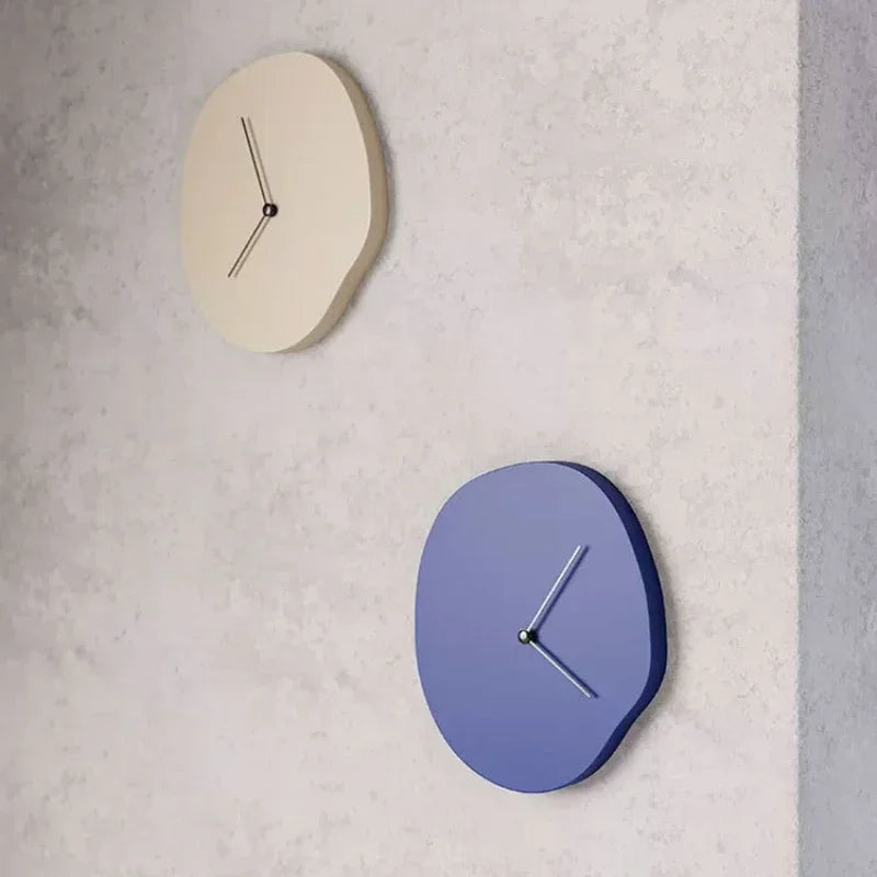 Two wall clocks, one beige and one blue, on a light gray wall.