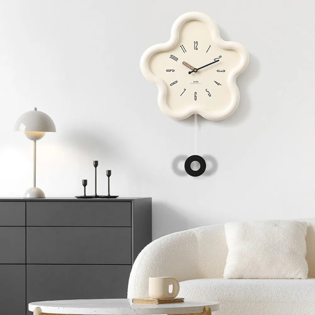 Floral-shaped wall clock on a white wall above a gray cabinet with a white sofa and lamp.