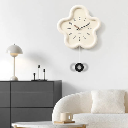 Floral-shaped wall clock on a white wall above a gray cabinet with a white sofa and lamp.