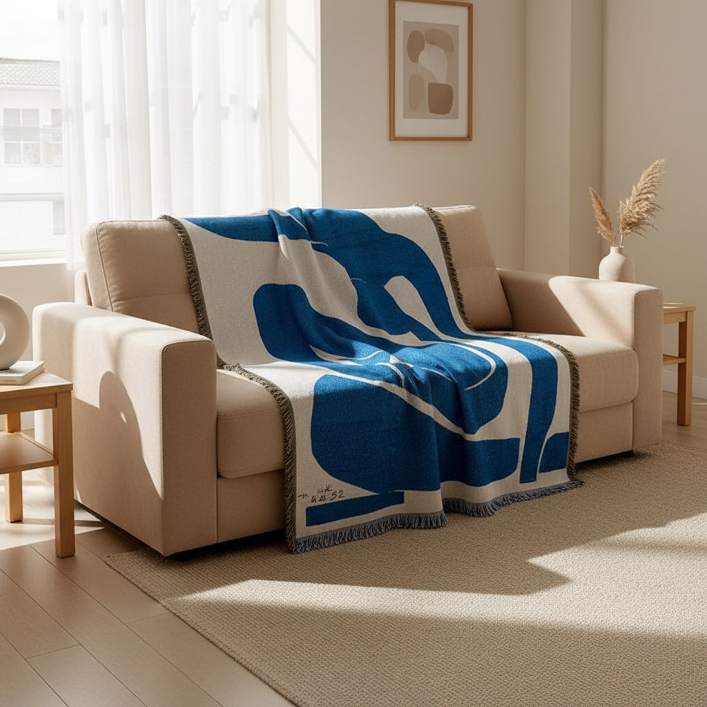 Blue and white abstract patterned blanket draped over a bed.