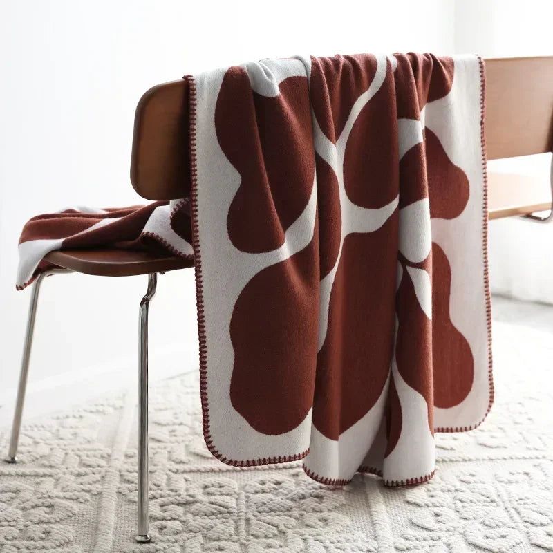 Brown and white patterned blanket draped over a chair on a light-colored floor.