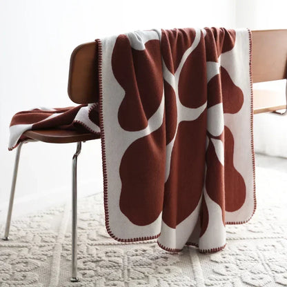 Brown and white patterned blanket draped over a chair on a light-colored floor.