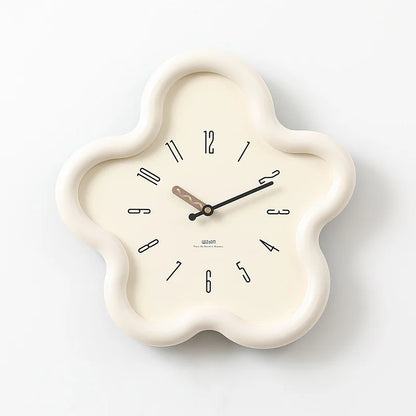 Decorative wall clock with a white frame on a gray surface against a white wall.