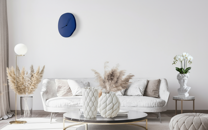 Modern living room with white sofa, decorative pillows, and a blue wall clock.