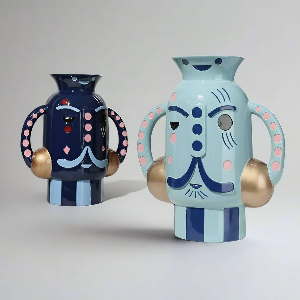 Two colorful ceramic vases with abstract face designs on a light gray background